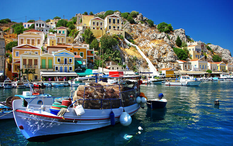 Ein Fischerboot legt am bunten Hafen von Symi an © leoks / Shutterstock.com